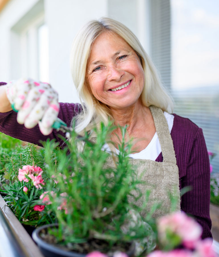 Adobe Stock | Halfpoint Weibliche Person gärtnert auf dem Balkon